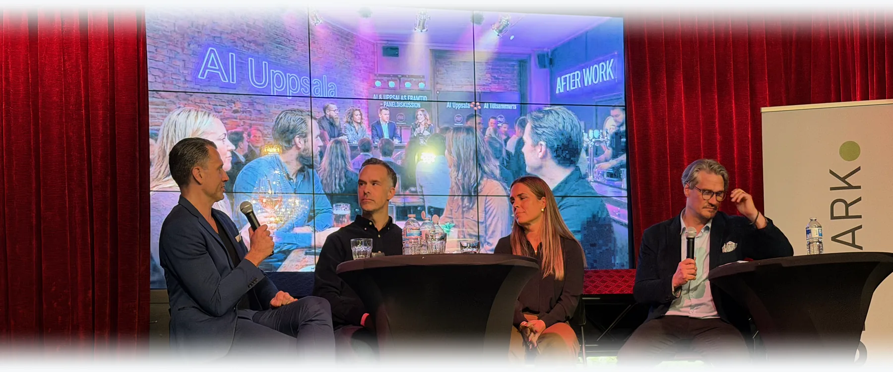 Four people in a panel conversation on a stage, in front of a screen reading AI Uppsala.