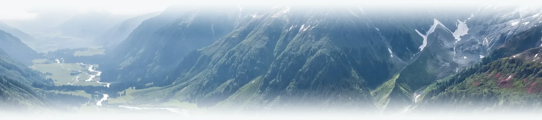 Green mountainsides and a valley with a winding river, under haze.